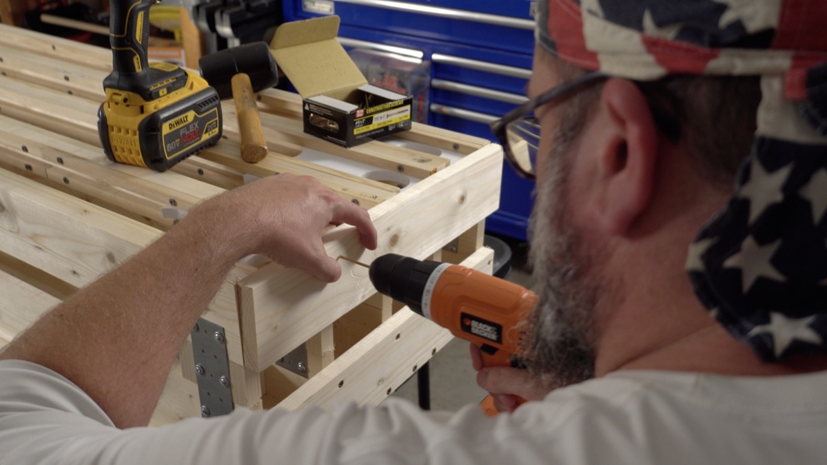 Driving a screw through a printed bottom block into the wood frame, garage workshop