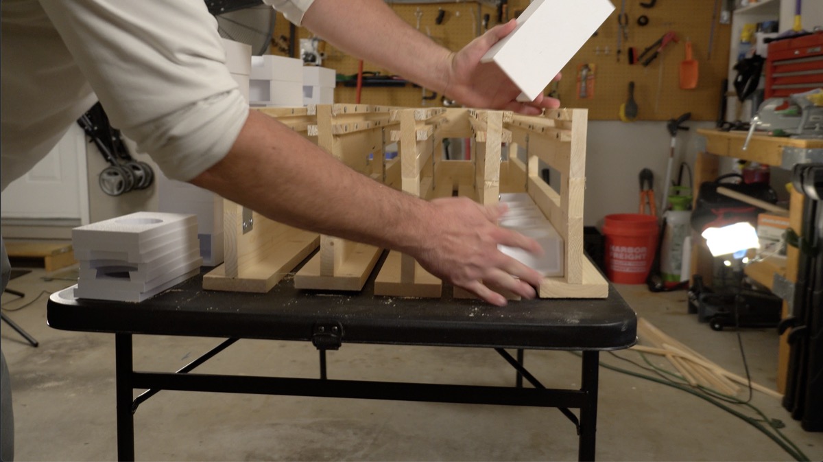 Lowering a 3D-printed spacer block into the wooden mortar rack frame