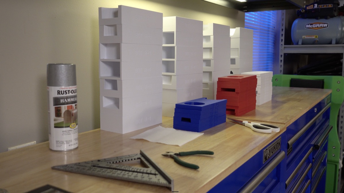 Stacks of finished 3D-printed mortar rack spacer blocks painted red, white, and blue